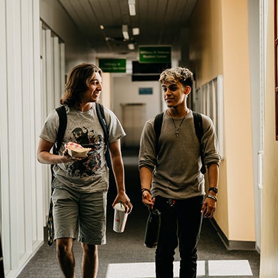 Two students walking down hall while talking