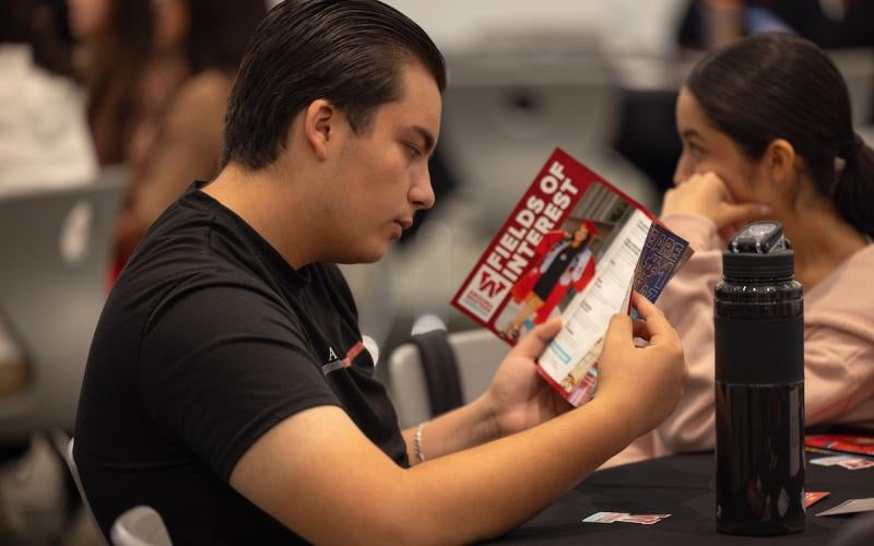 Student reads an AWC pamphlet at a 2023 High School Senior Day event.
