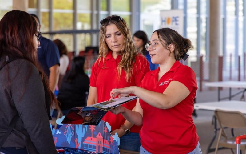 Representatives from the University of Arizona speak with a student at the Yuma Transfer and Career Expo in October 2024.