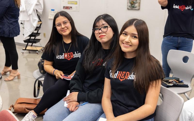 Three female students wearing T-shirts with the leadHERship logo