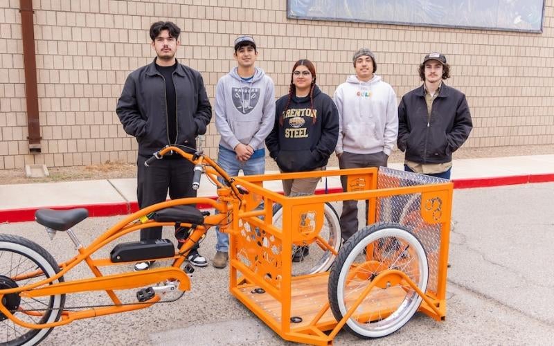 The AWC Welding team stands behind the completed front-loading bicycle designed for Mason Drake.