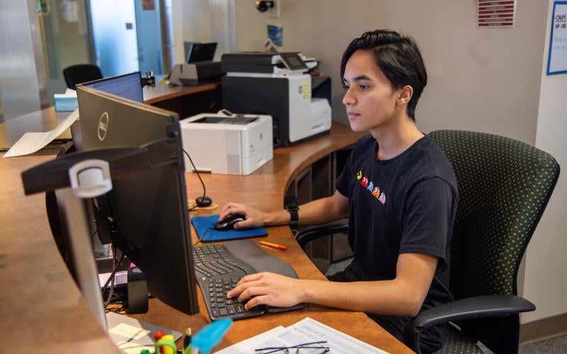 Person works at a computer desk with monitor, keyboard, and mouse.