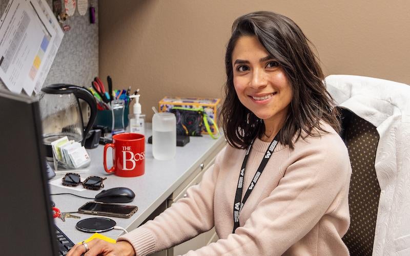 Human Resources employee sits at an office desk, typing on her keyboard