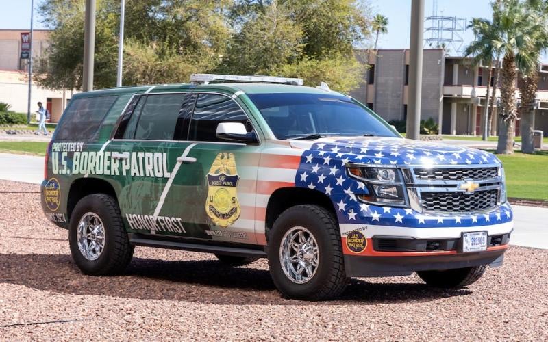 US Border Patrol car parked on the AWC campus. The car features a custom wrap featuring an American flag, border patrol agent, and an enlarged gold badge.