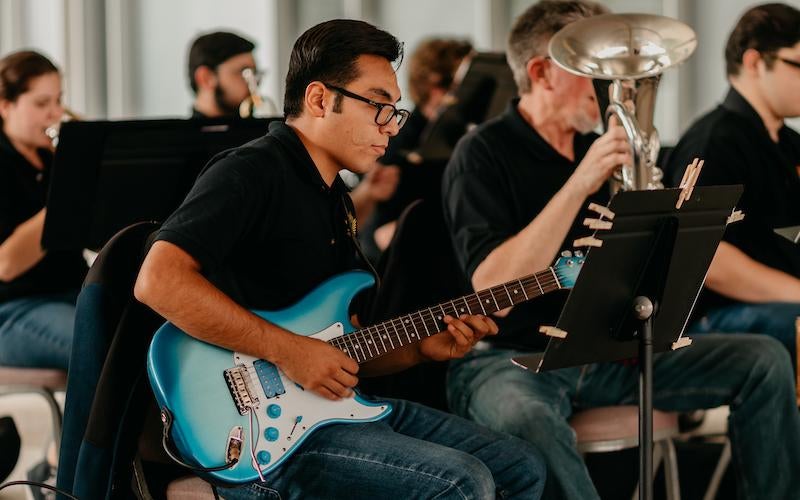 AWC Pep Band musician plays the electric guitar during the 2023 Courtyard Concert at AWC.