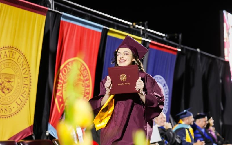 Graduate holds up a diploma from ASU Local at the AWC Commencement.