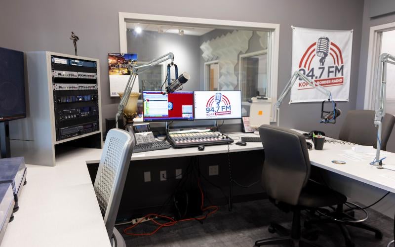 Inside the KOFA-Border Radio cabin, with a poster that says "94.7 FM KOFA-Border Radio."
