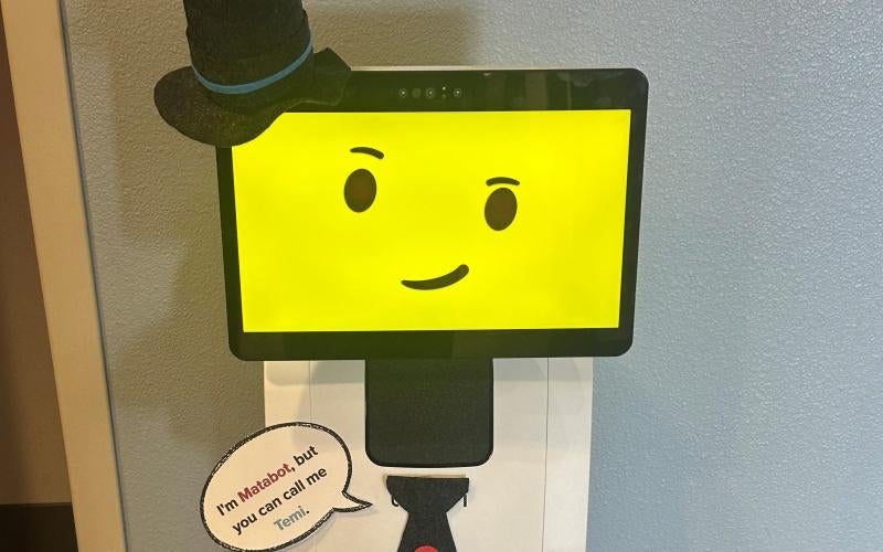 Decked out in a paper top hat and tie, Matabot greets students at the SLLC with a screen that reads, "Hello Welcome to San Luis" and a speech bubble nametag that reads, "I'm Matabot, but you can call me Temi"