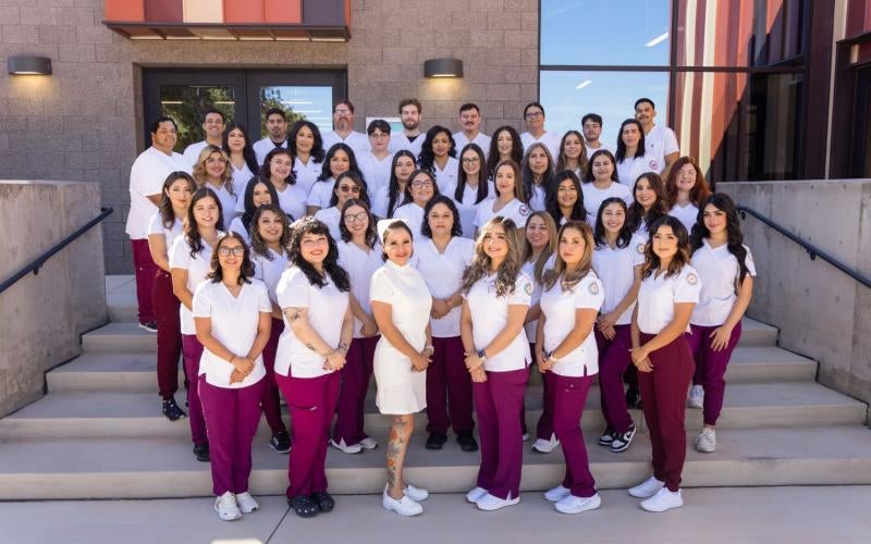 Graduates from the nursing program stand together in their nursing uniforms