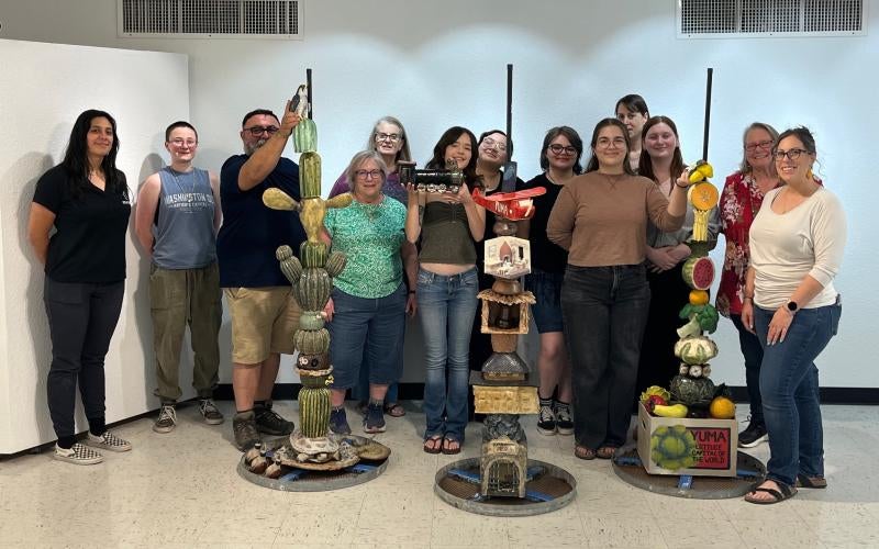 AWC students and professors stand behind their totem sculptures—“Yuma’s Flora & Fauna,” “Yuma’s History,” and “Yuma’s Bounty.” From left to right: Katie Kilgore, Rose Webber, Professor Miguel Pulido, Ceramics Professor Rebecca Shelby, Janet Carper, Allison Barnes, Jenny Alvarez, Grace Crittenden, Ramsey Fischer, Stephanie Slinski, Meghan Smith, Jackie Steinhoff, and Hilary Mulherin.