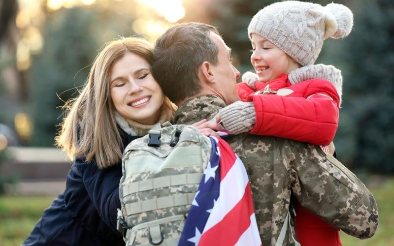 Veteran in uniform hugs his wife and daughter