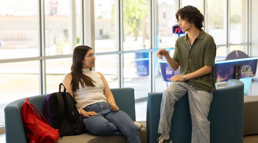Two students sit in front of a window talking